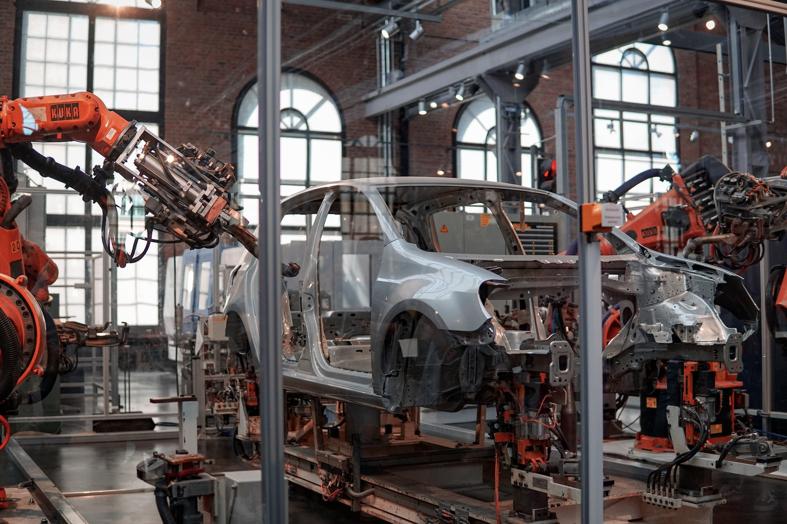 gray vehicle being fixed inside factory using robot machines advanced manufacturing processes
