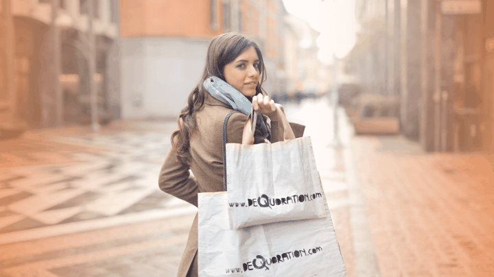 woman holding two shopping bags looking over her shoulder smiling