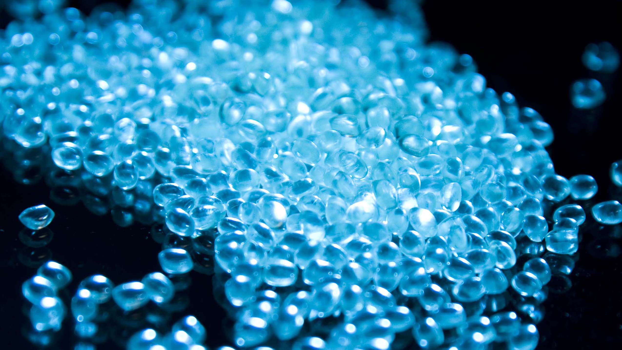 glowing blue pulymer pellets on a black background