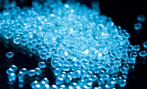 glowing blue polymer pellets on a black background