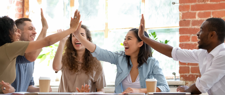 Employees giving each other a collective high five around a table