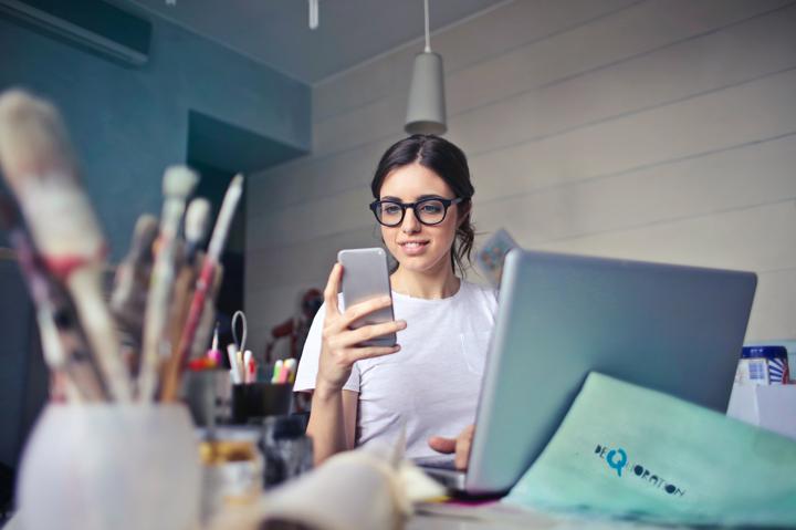 Lady working on laptop and looking at cell phone