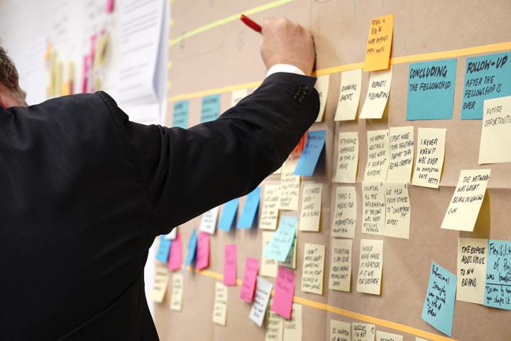 Hand writing notes on post-its on corkboard