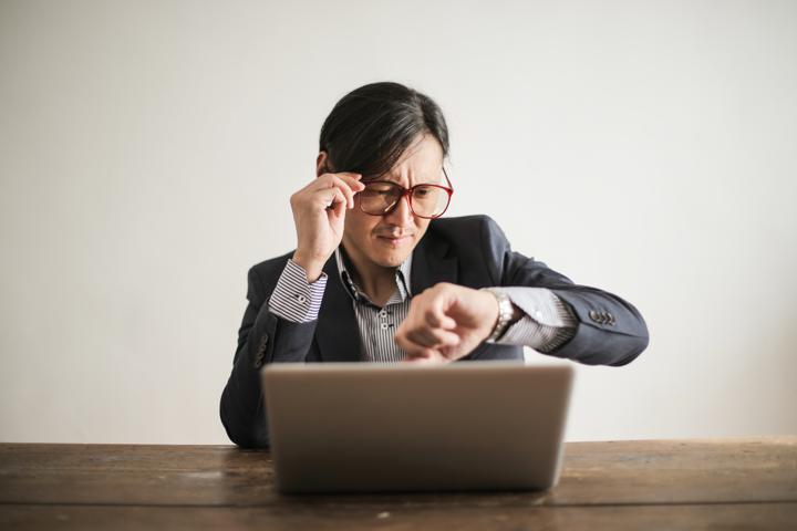 Person looking at watch in front of laptop