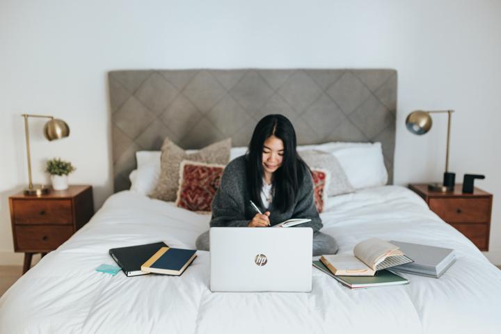 woman in black hijab sitting on bed using macbook