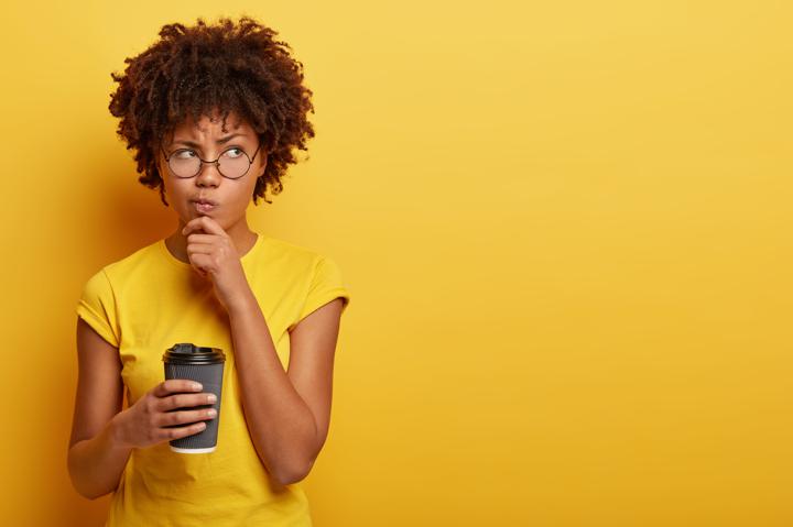 Woman in yellow contemplating over yellow background