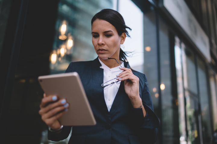 Photograph of executive holding glasses and tablet