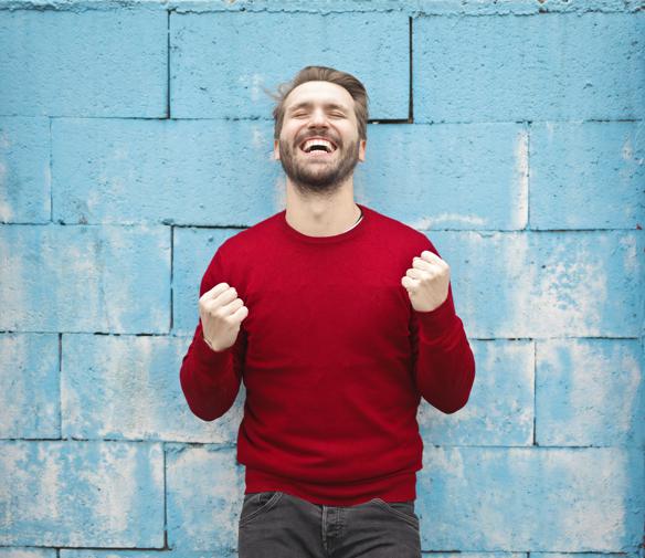 man wearing red long-sleeved shirt standing beside wall is excited about lead generation