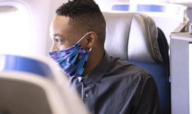 Man wearing a mask, looking out window in United Polaris