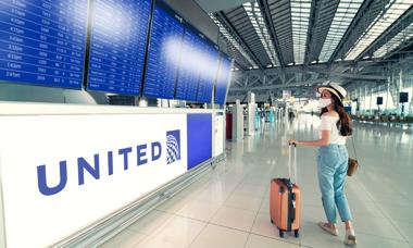 Woman looking at United departures board at airport