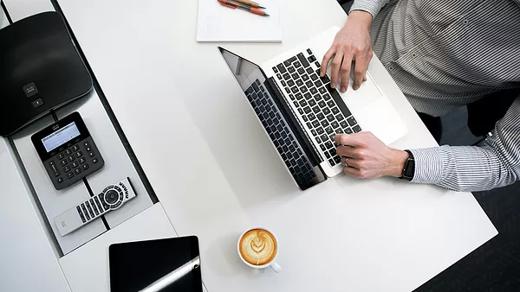 Person typing on a laptop with a cup of coffee