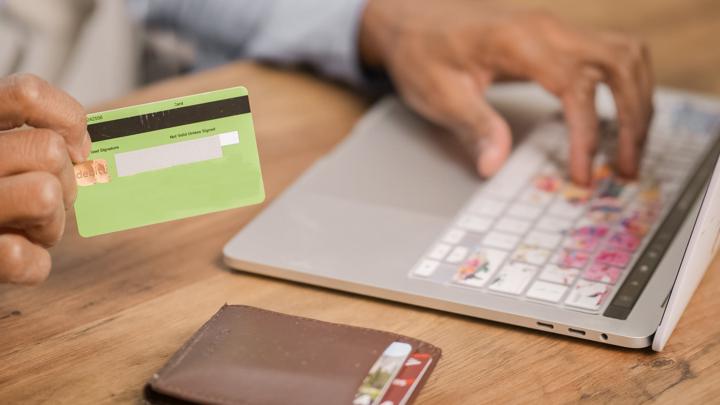 Person holding credit card and laptop